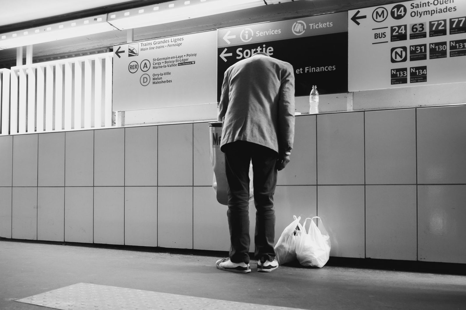 Man seen from behind in a Paris metro corridor in front of signs for Sortie, RER A and line 14