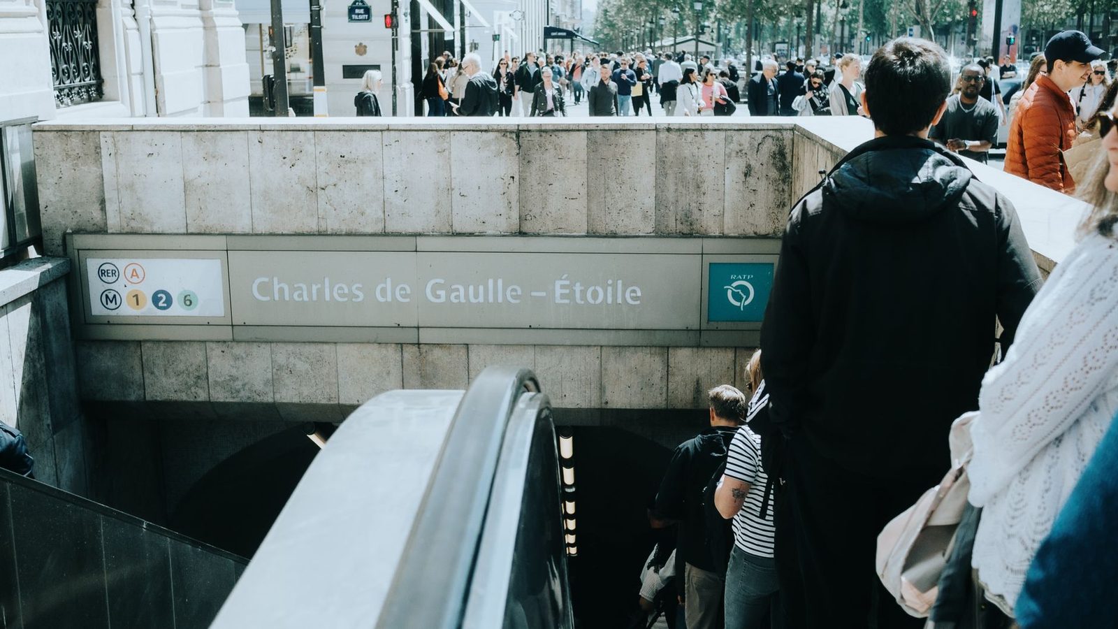 Entrance to Charles de Gaulle-Étoile station with signs for RER A and metro lines 1, 2, 6 and passengers