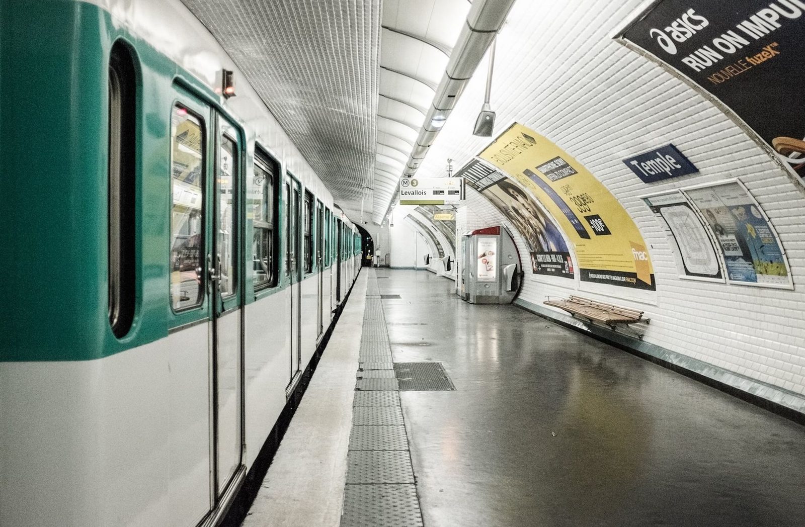 Metro train standing at the platform in Temple station, empty platform and advertising posters on the tiled wall
