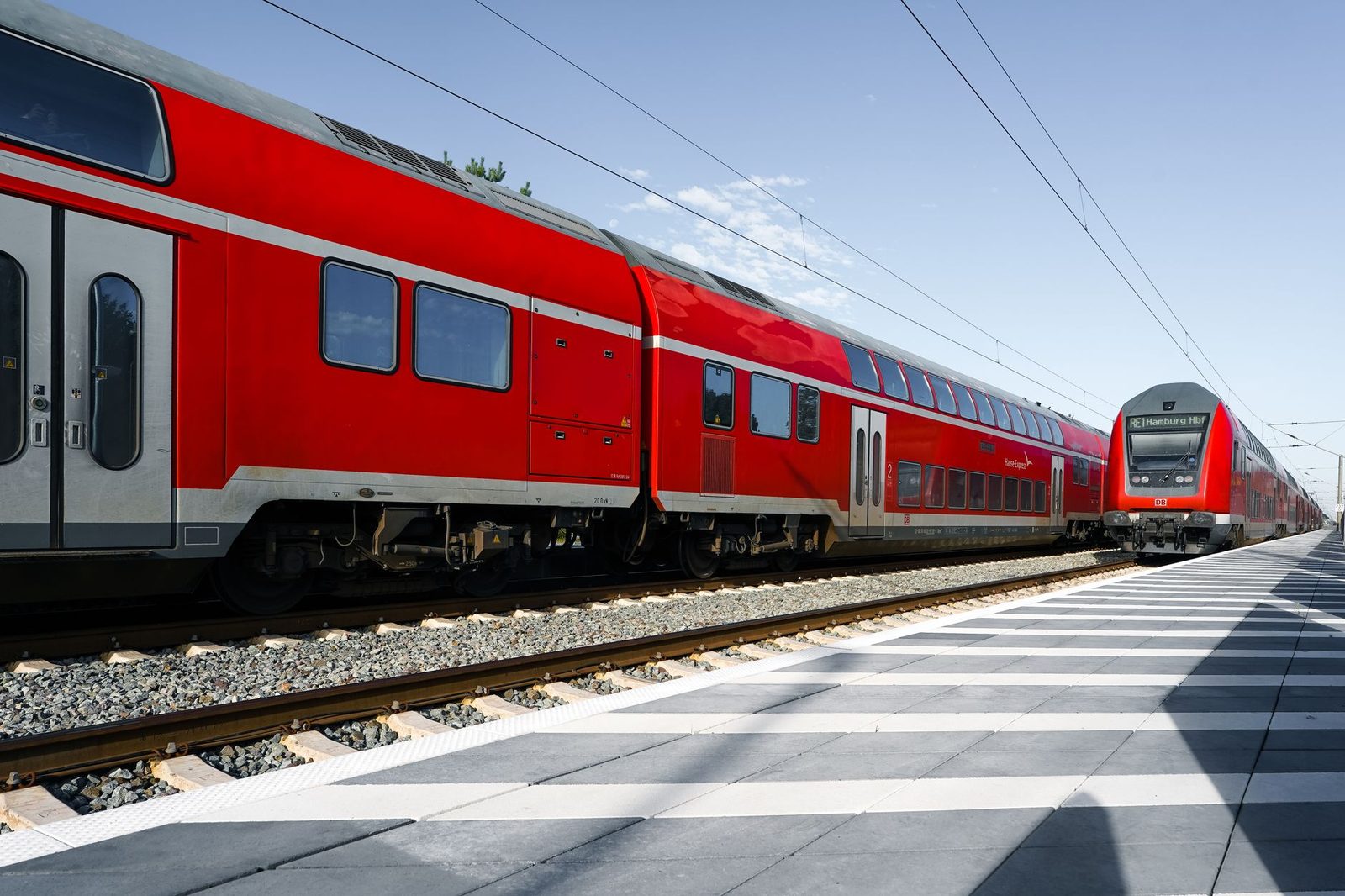 Red double-deck regional trains at the platform, one showing Hamburg Hbf as its destination