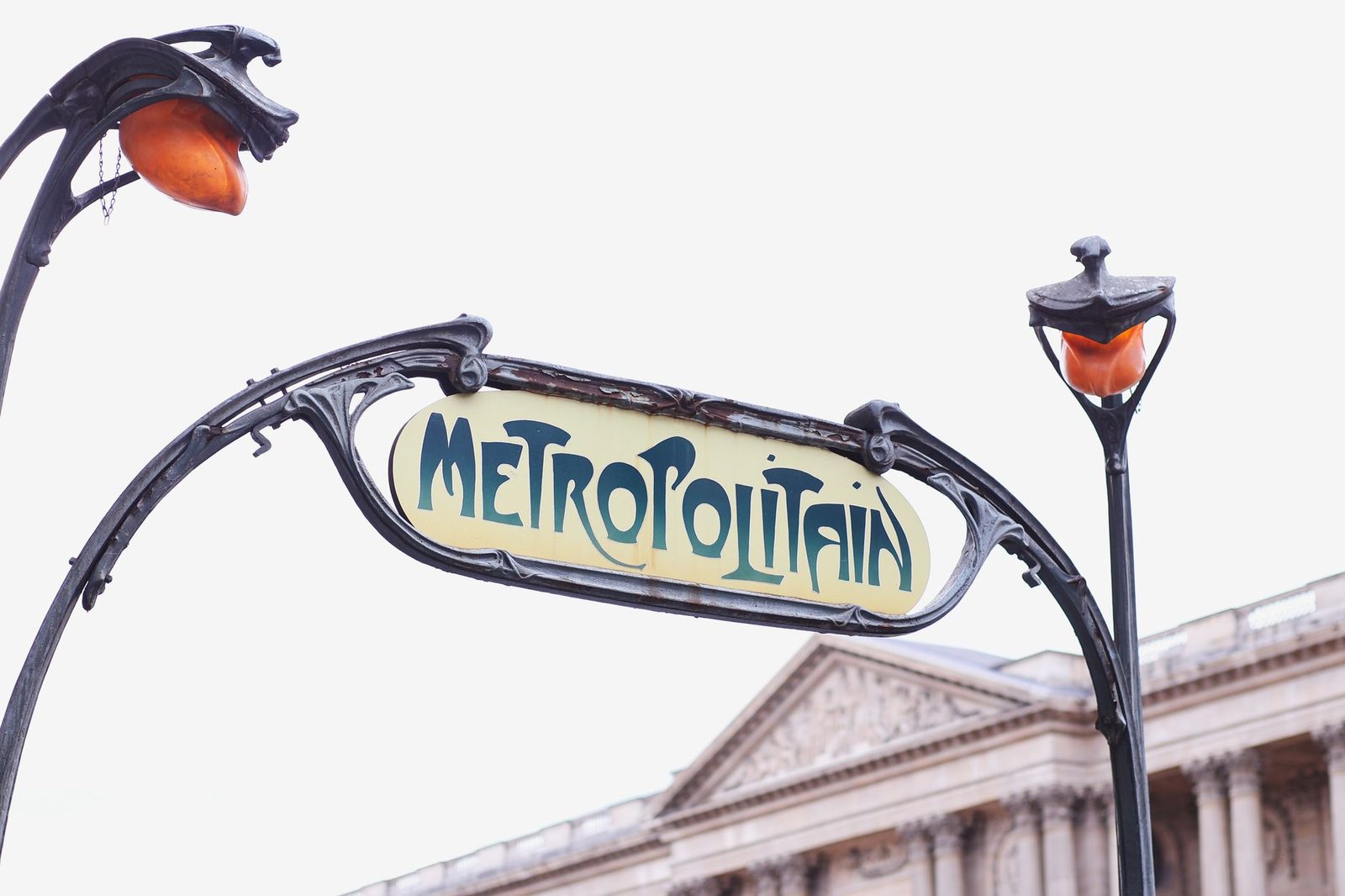 Panneau Métropolitain Art nouveau et lampadaires devant une façade à colonnes à Paris