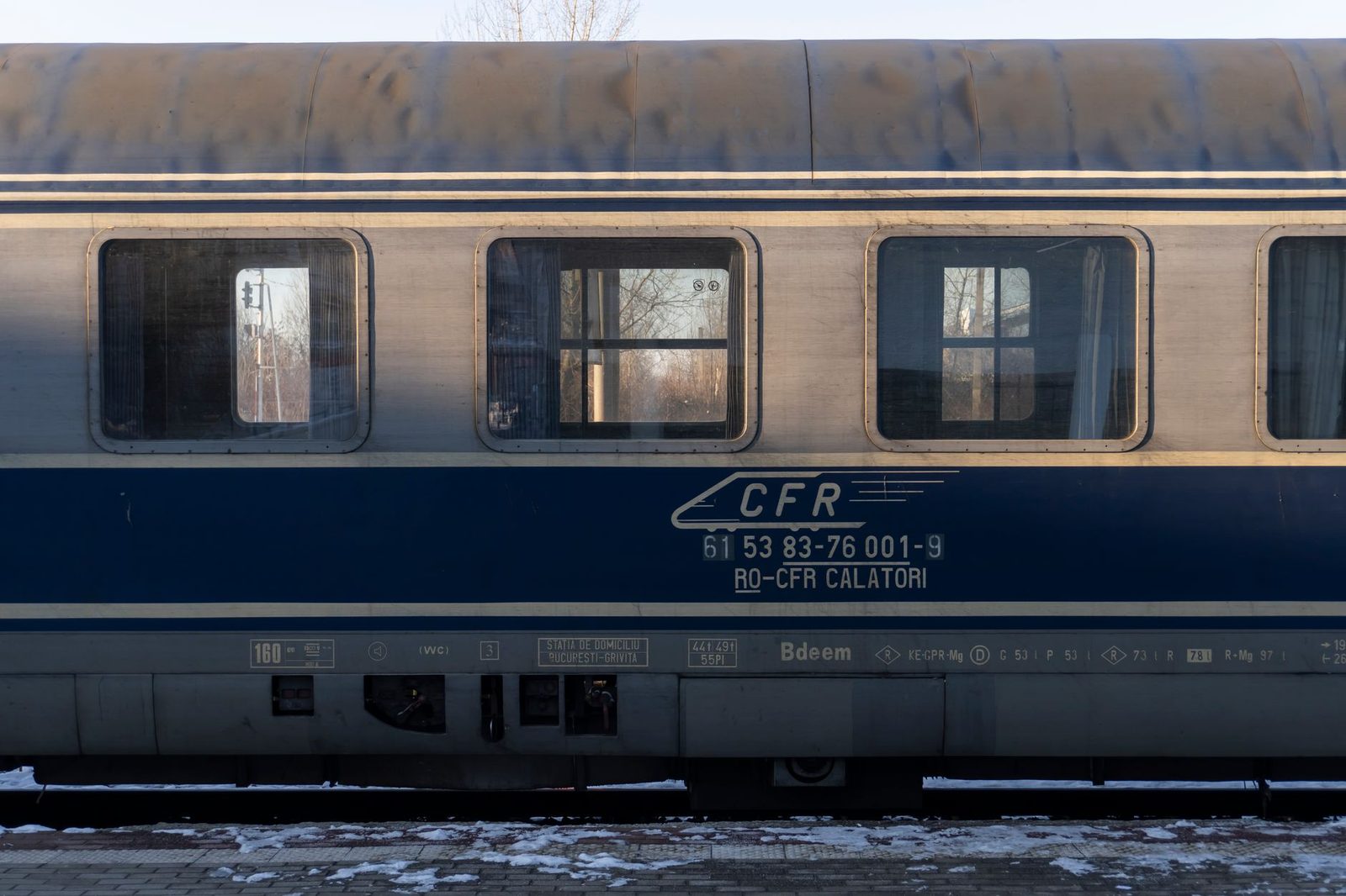 Voiture-couchettes bleue CFR à quai, fenêtres avec rideaux, neige au sol en hiver