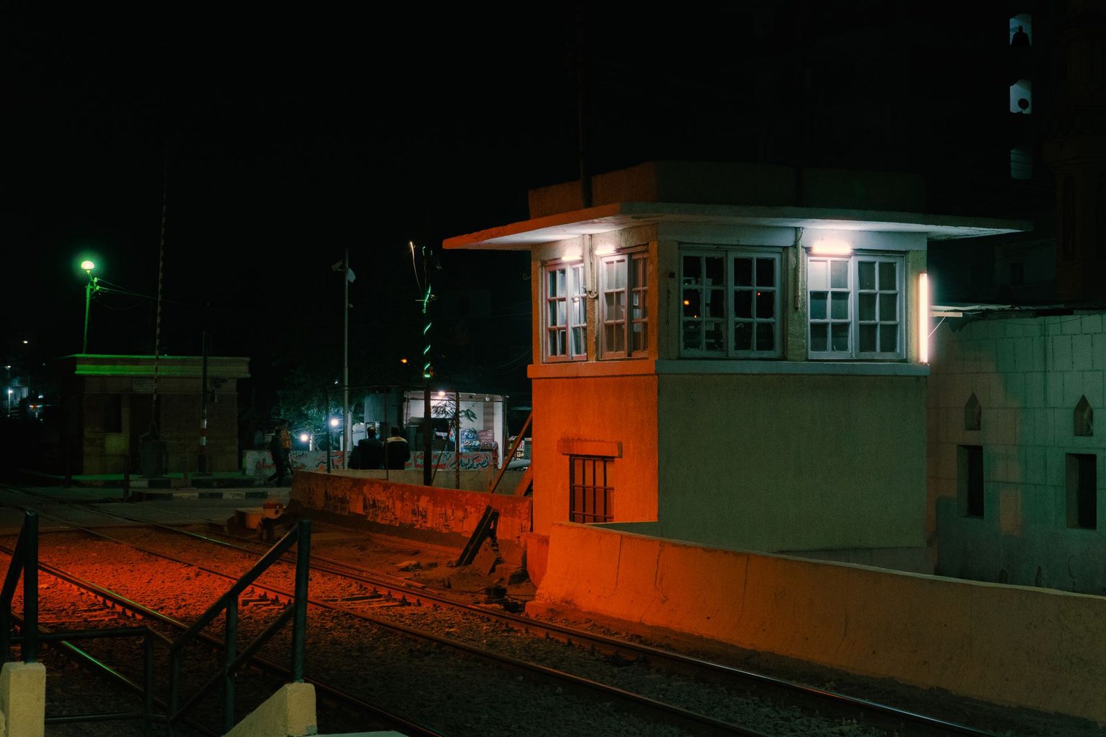 Railway tracks lit at night in front of a signal box glowing orange
