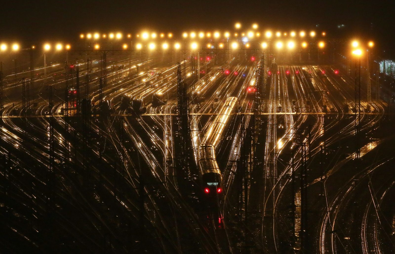 Railway tracks lit up at night with a train running through a marshalling yard