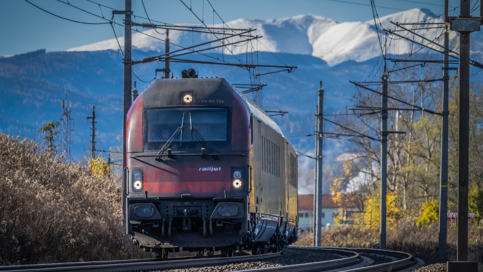 Un train Railjet ÖBB passant devant des montagnes autrichiennes enneigées