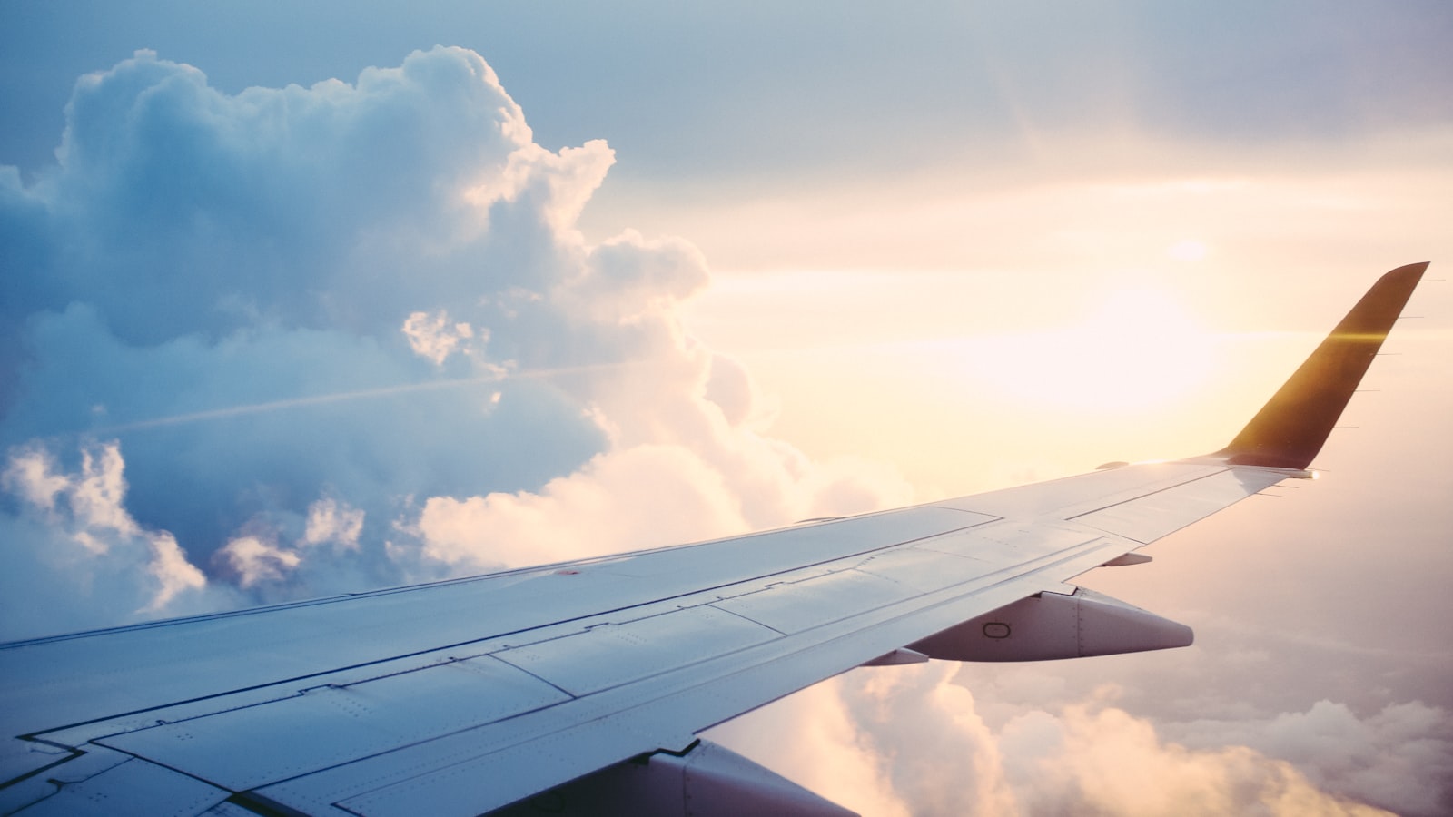 Asa de avião acima das nuvens ao pôr do sol numa rota europeia de curta distância