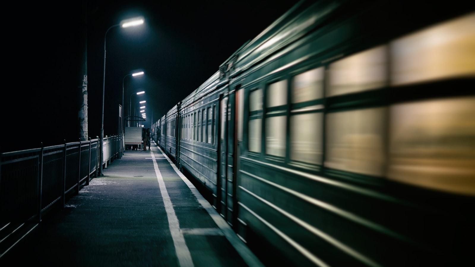 A night train departing a lamplit platform in the dark
