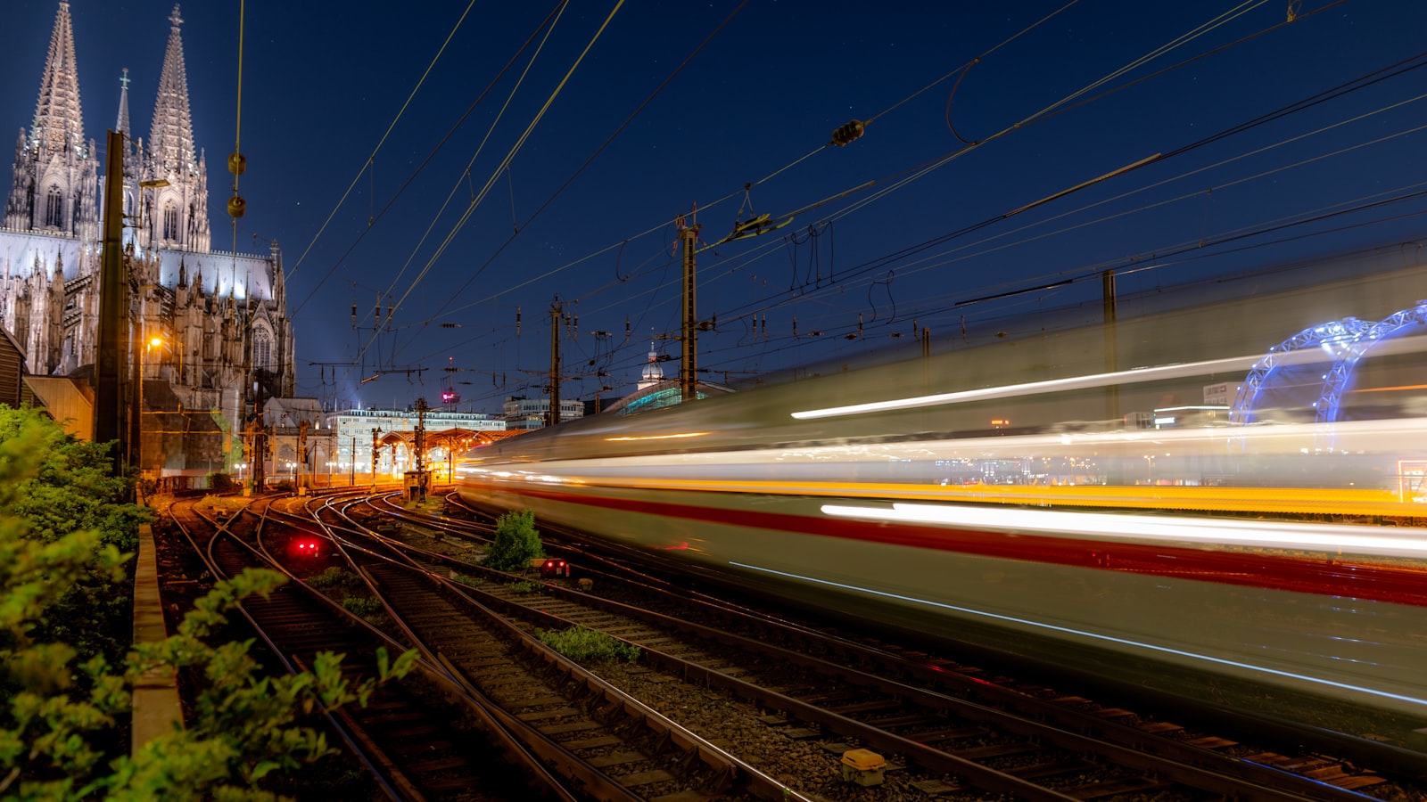 Un train à grande vitesse passe devant la cathédrale de Cologne au crépuscule, en Allemagne