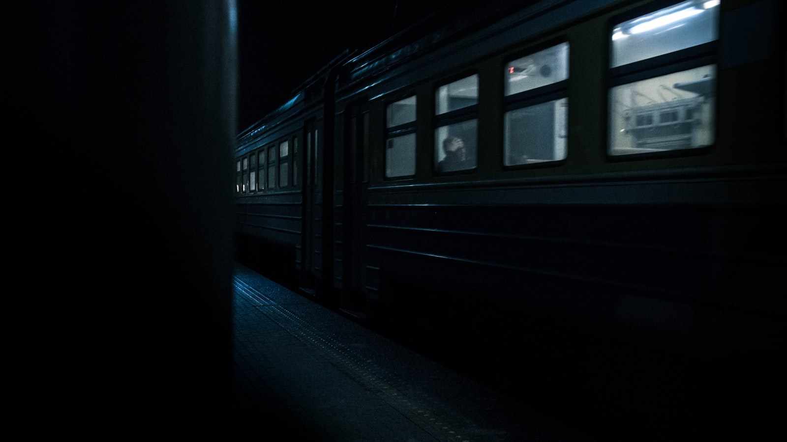 Un tren nocturno europeo cruzando una estación con las ventanillas iluminadas