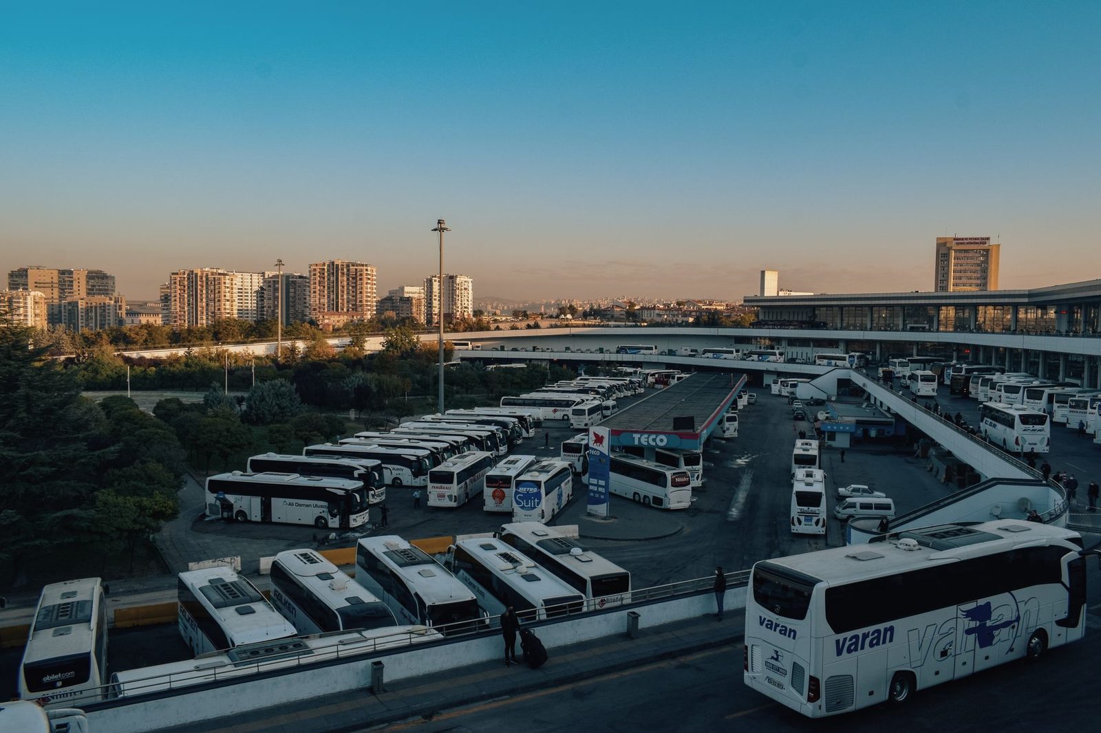 Vue aérienne d'une gare routière avec de nombreux autocars blancs stationnés au coucher du soleil