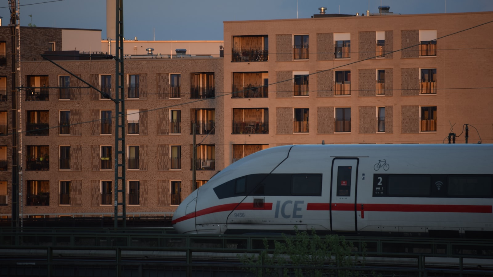 Un treno ICE della Deutsche Bahn che attraversa Amburgo all'ora dorata, con palazzi in mattoni sullo sfondo