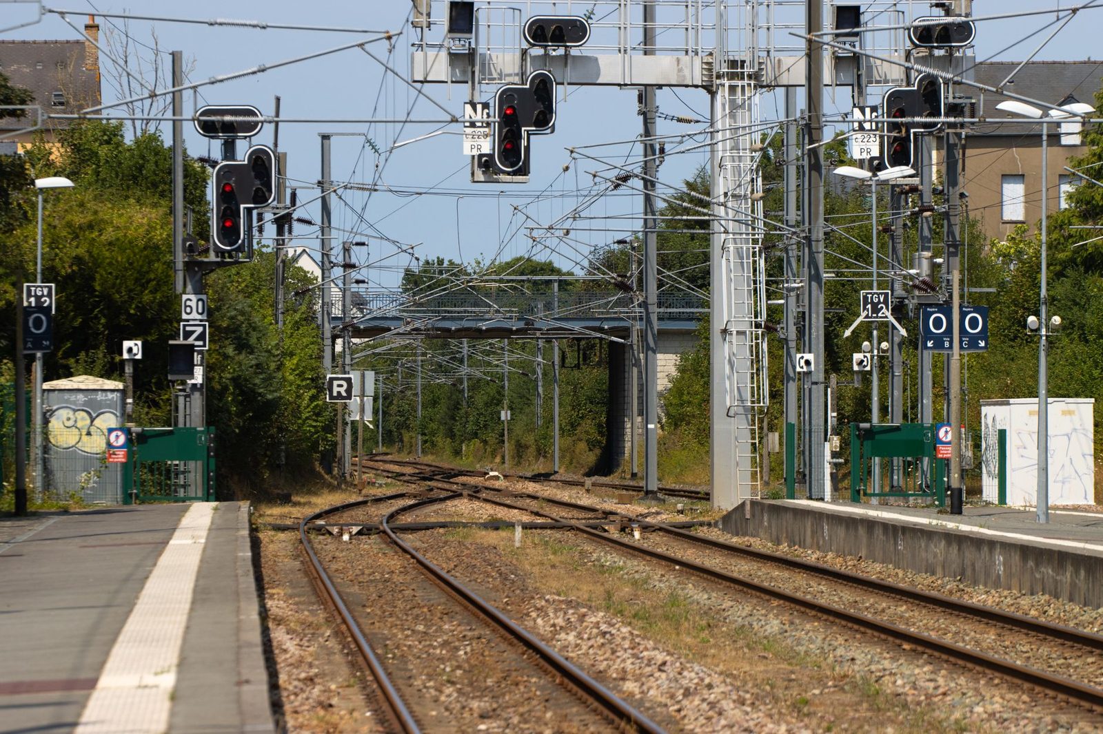 Railway tracks with a set of points, light signals and overhead lines seen from a station platform