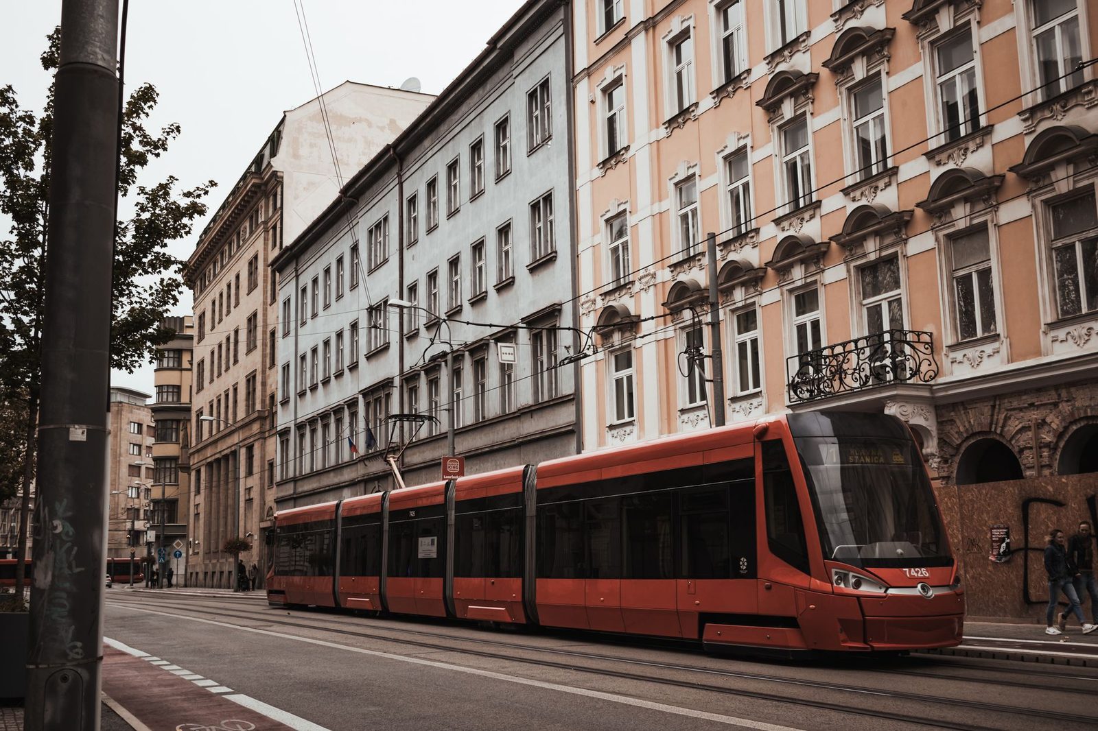 Tramway rouge moderne circulant dans une rue bordée d'immeubles anciens en ville