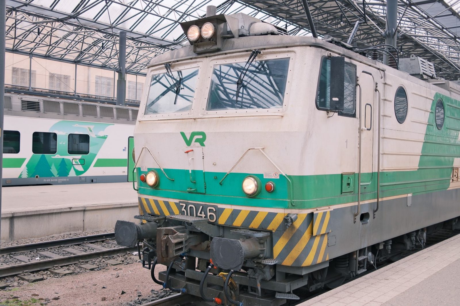 Grün-weiße VR-Elektrolokomotive Nummer 3046 am Bahnsteig unter der Bahnhofshalle