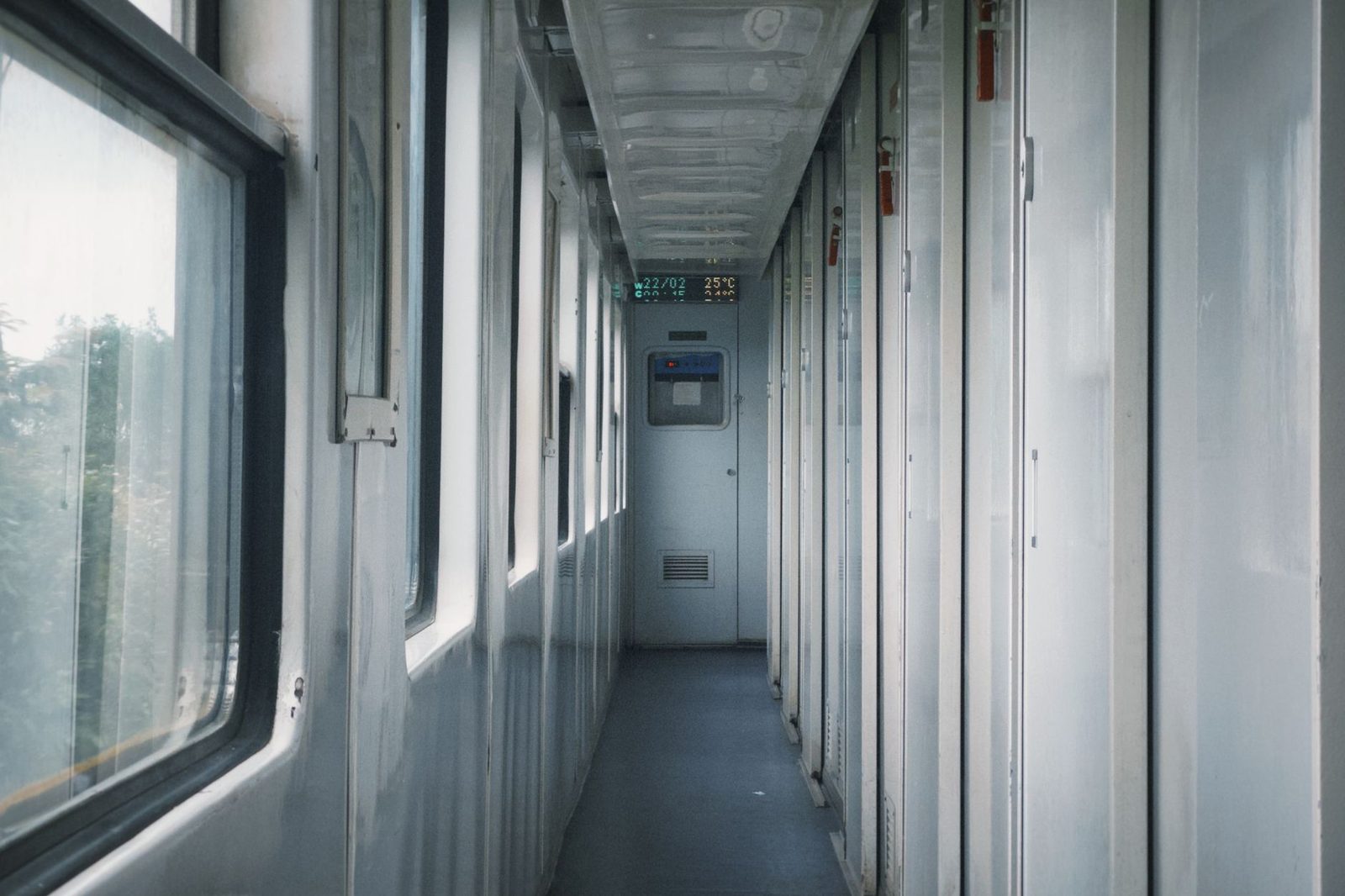 Narrow corridor of a train sleeping car with compartment doors and windows